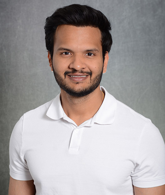 A headshot of Siddharth Singh smiling standing in front of a grey background.